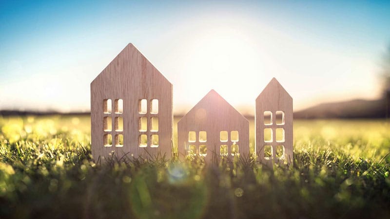 3 Dekoholzhaeuser in Wiese als Sinnbild fuer Bauen mit Holz